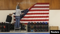 Workers take down a U.S. flag following a campaign stop by Democratic presidential candidate Hillary Clinton at the Family Fun Center in Adel, Iowa, Jan. 27, 2016.