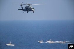 A U.S. MH-60 Seahawk helicopter flies over Iranian Revolutionary Guard patrol boats, Dec. 21, 2018.