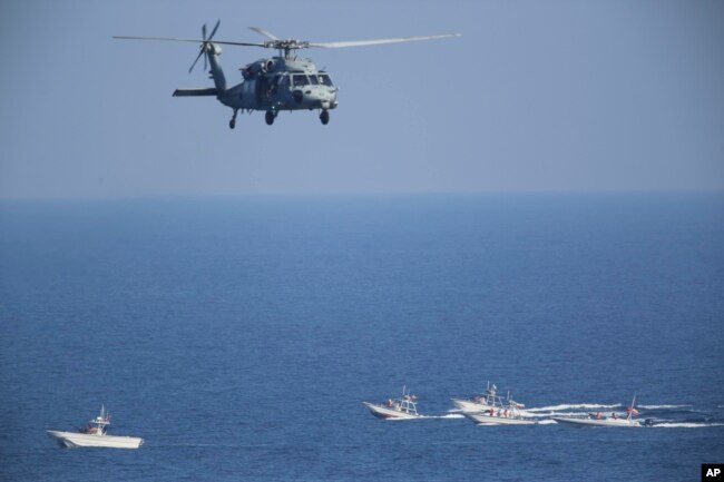 A U.S. MH-60 Seahawk helicopter flies over Iranian Revolutionary Guard patrol boats, Dec. 21, 2018.