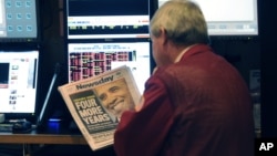 A trader on the floor of the New York Stock Exchange looks at the front page of a newspaper the day after Presiden Obama was re-elected, November 7, 2012. 