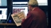 Một nhà giao dịch làm việc tại Sàn giao dịch Chứng khoán New York đọc nhật báo với bản tin hàng đầu về việc Tổng thống Obama tái đắc cử, 7/11/12
