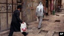 Seorang Yahudi ortodoks berjalan di belakaang seorang pria Palestina di kota tua Yerusalem (foto: ilustrasi).