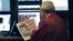 A trader on the floor of the New York Stock Exchange looks at the front page of a newspaper the day after Presiden Obama was re-elected, November 7, 2012. 