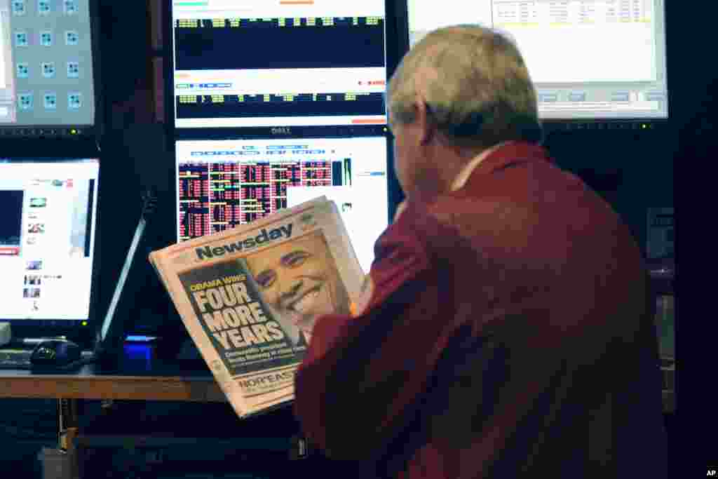 A trader on the floor of the New York Stock Exchange looks at the front page of a newspaper the day after Presiden Obama was re-elected, New York, November 7, 2012. 