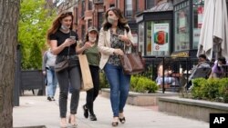FILE - Pedestrians walk along Boston's fashionable Newbury Street in Massachusetts. 