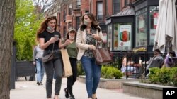 FILE - Pedestrians walk along Boston's fashionable Newbury Street in Massachusetts. 