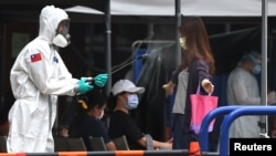 一名台湾士兵向一名离开台北新冠病毒检测中心的女子身上喷洒消毒药水。（2021年5月18日）