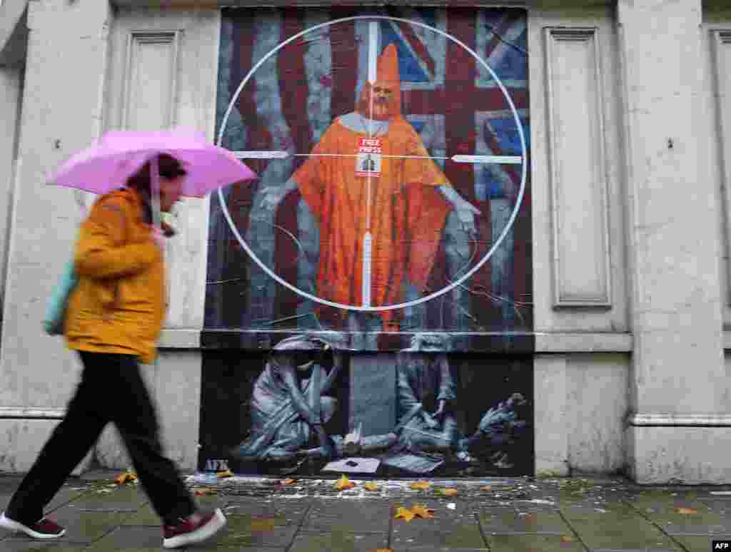 A pedestrian passes a graffiti mural of WikiLeaks founder Julian Assange, near Westminster Magistrates Court in London.