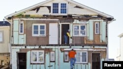 Warga menaiki tangga di luar rumahnya yang hancur karena Badai Sandy di Ortley Beach, New Jersey (7/1). (Reuters/Tom Mihalek)