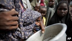 A woman carrying her baby queues for food in a camp established by the Somali Transitional Federal Government for the internally displaced people in Mogadishu.