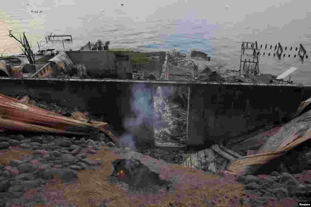 A fire smolders amidst the remains of a waterfront home on Lake Chelan destroyed by the Chelan Complex fire in Chelan, Aug. 24, 2015.