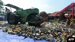 A steam roller machine destroys hundreds of alcohol drinks, pornographic and pirated video DVDs in a Jakarta police station, July 8, 2013.