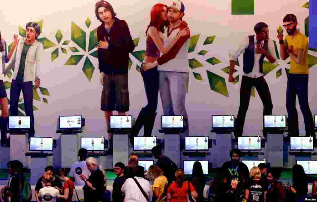 Visitors play &quot;Sims 4&quot; at the Electronic Arts EA exhibition stand during the Gamescom 2013 fair in Cologne, Germany.
