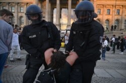 A protester is held by German riot policemen in front of the Reichstag building, which houses the Bundestag lower house of parliament, at the end of a Berlin demonstration called by far-right and COVID-19 deniers on Aug. 29, 2020.