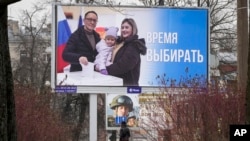 Warga berjalan melewati papan iklan yang mempromosikan pemilihan presiden dengan seruan "Waktunya Memilih" dalam Bahasa Rusia, di St. Petersburg, Rusia, pada 7 Maret 2024. (Foto: AP)