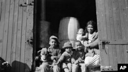 FILE - Driven from their home by the flood, this woman and her children have taken up residence in this box car in Elaine, Arkansas.