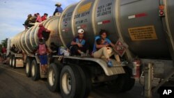 Una mujer con su hijo en brazos viaja sentada en una plataforma sobre la rueda de un camión cisterna, en Niltepec, en el estado de Oaxaca, México, el 30 de octubre de 2018.