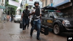 Policemen return after rafter a raid on a building in Dhaka, Bangladesh, Tuesday, July 26, 2016.