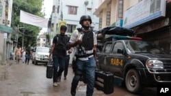 방글라데시 경찰은 26일 수도 다카 인근에서 벌어진 총격전에서 이슬람 과격분자 9 명을 사살했다고 밝힌 가운데, 상황이 종료된 후 경찰관들이 소총이 든 가방을 들고 철수하고 있다.