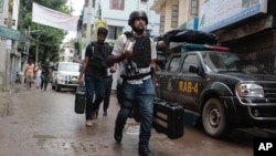 FILE - Policemen return after rafter a raid on a building in Dhaka, Bangladesh, July 26, 2016.