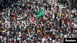 A national flag is seen amidst the supporters of Muhammad Tahirul Qadri, Sufi cleric and leader of political party Pakistan Awami Tehreek (PAT), as they gather to listen to his speech during the Revolution March in Islamabad, Aug. 16, 2014.
