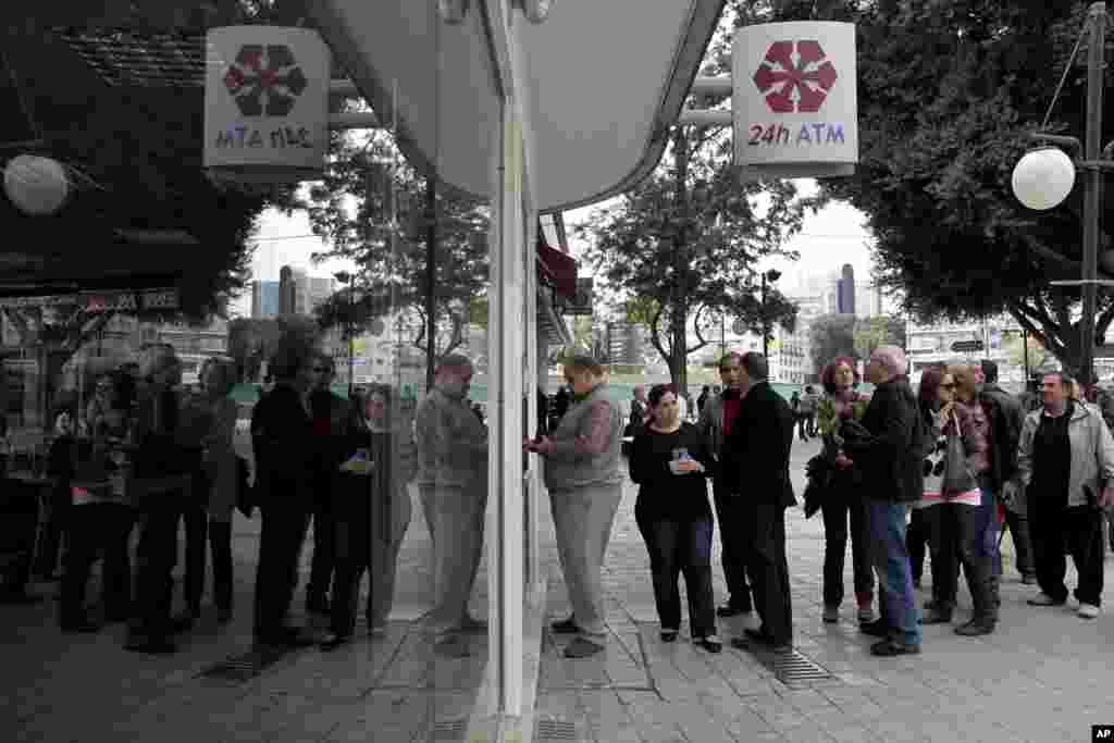 People line up at an ATM outside a closed Laiki Bank branch in Nicosia, Cyprus, March 21, 2013. 