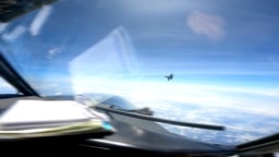 In this image from video provided by the U.S. Navy, a Chinese J-16 fighter flies close to a U.S. RC-135 aircraft flying in international airspace over the South China Sea on May 26, 2023.