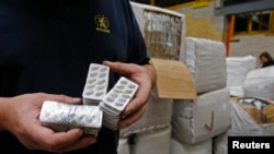 FILE - A Belgian customs officer shows tablets of counterfeit drugs at Brussels' airport, Oct. 3, 2008.