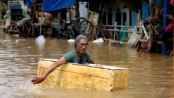 Um homem usa uma caixa de esferovite flutuante para se deslocar numa rua inundada de Jakarta, capital da Indonésia. 2 Janeiro 2020