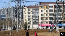 People walk past apartment blocks on the outskirts of Beijing, March 9, 2011