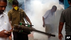 A municipal worker fumigates an area outside a train station to check the spread of mosquito-borne diseases in Mumbai, India, Sept. 3, 2016. 