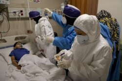 Enfermeras toman una muestra de Parham, un niño de 7 años, para detectar la enfermedad del coronavirus (COVID-19), en un hospital, en Teherán, Irán, el 8 de julio de 2020. WANA (Agencia de Noticias de Asia Occidental) Abdollah Heidar.