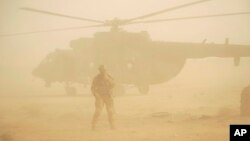 FILE - Russian soldier stands guards as military helicopter takes off at an airport in Deir el-Zour, Syria, Sept. 15, 2017.