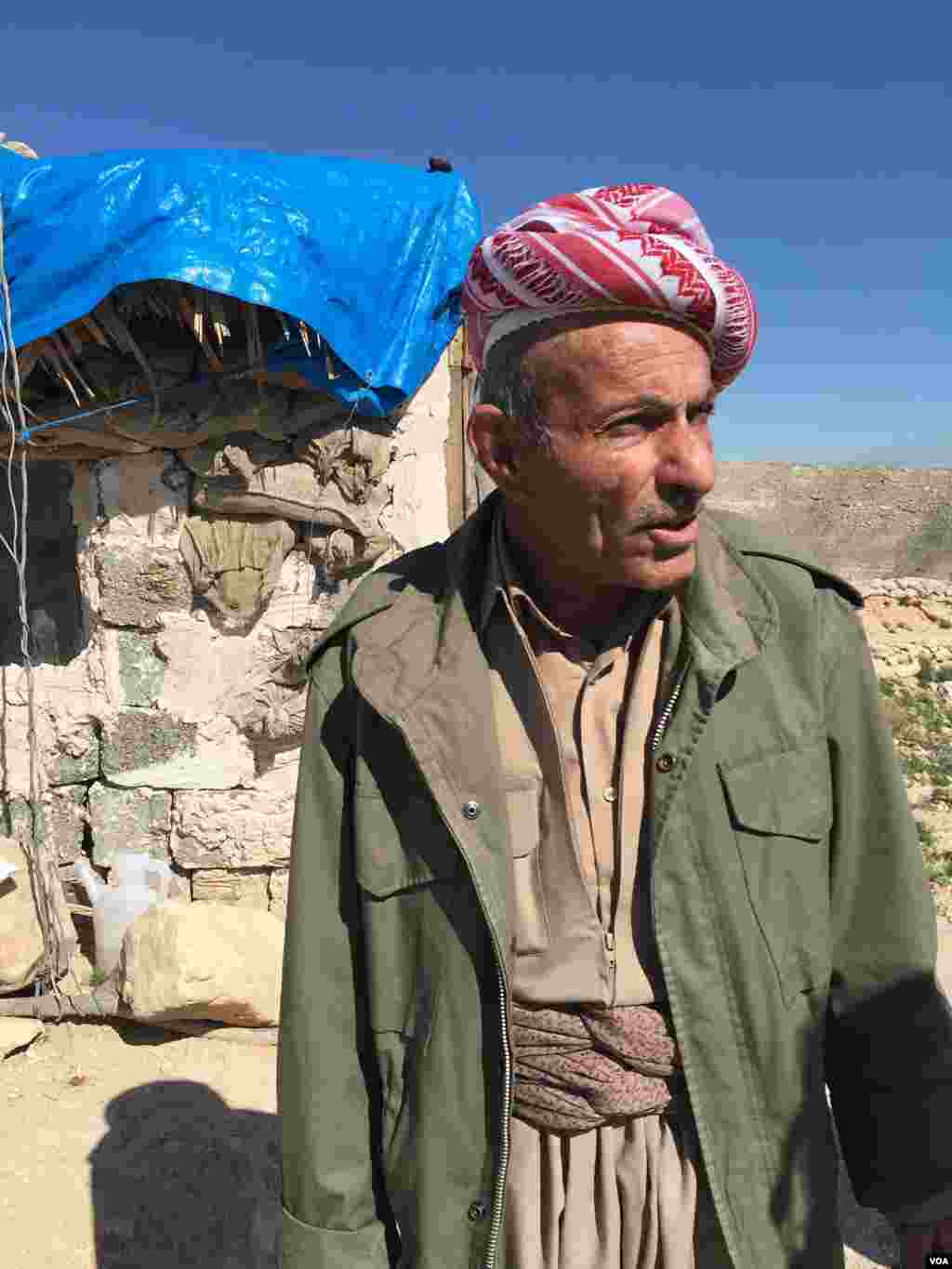 Born in 1938, elder Peshmerga fighter and now a volunteer, Omar Mirhan talks about the Kurdish fight for the Makhmour area, standing at a hill overlooking the town, March 8, 2016. (S. Behn/VOA)