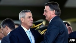 FILE - Brazilian President Jair Bolsonaro, right, greets his vice presidential candidate, Walter Souza Braga Netto during the celebration of Soldier's Day at the Army headquarters in Brasilia on Aug. 25, 2022.