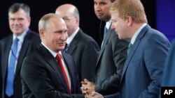 Vladimir Putin saluda a Myron Brilliant, vicepresidente ejecutivo de la Cámara de Comercio de Estados Unidos, en San Petersburgo.