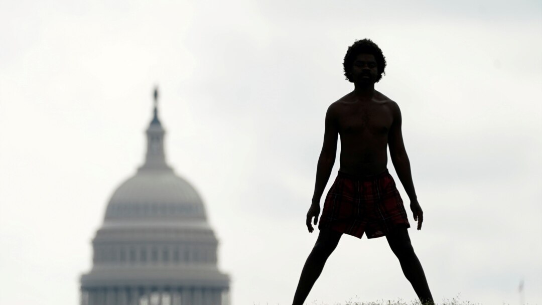 S kupolom američkog Kapitola u pozadini, beskućnik po imenu Damu proteže se na National Mall-u u Washingtonu.