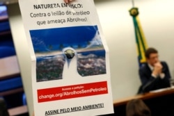 A sign reads "Nature at Risk: Against the Abrolhos Threatening Oil Auction" during protest against the opening of the area near the Abrolhos National Park for oil exploration. Brazil's environment minister Ricardo Salles speaks, in Brasilia, Brazil.