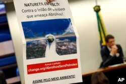A sign reads "Nature at Risk: Against the Abrolhos Threatening Oil Auction" during protest against the opening of the area near the Abrolhos National Park for oil exploration. Brazil's environment minister Ricardo Salles speaks, in Brasilia, Brazil.