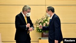 Perdana Menteri Jepang Yoshihide Suga (kanan) menyapa Presiden Komite Olimpiade Internasional (IOC) Thomas Bach (Kiri) dalam pertemuan mereka di Tokyo pada 16 November 2020. (Foto: Kazuhiro Nogi via REUTERS)