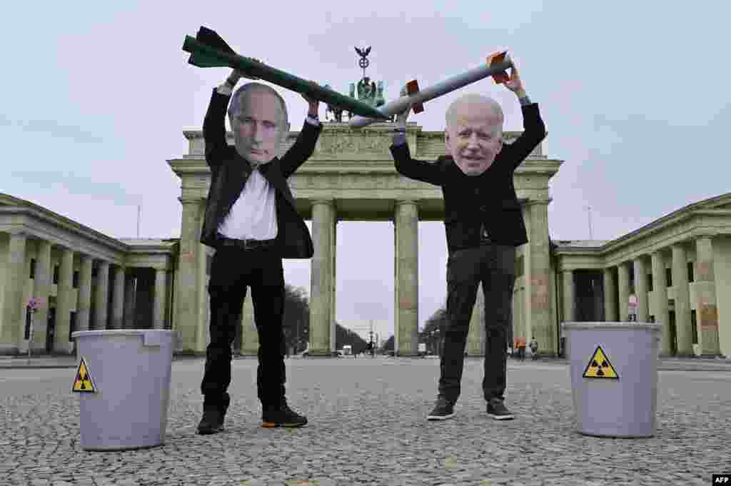 Peace activists wearing masks of Russian President Vladimir Putin, left, and U.S. President Joe Biden pose with mock nuclear missiles in front of Berlin&#39;s Brandenburg Gate in an action to call for more progress in nuclear disarmament. 