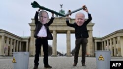 Aktivis perdamaian mengenakan topeng bergamba Presiden Rusia Vladimir Putin (kiri) dan Presiden AS Joe Biden berpose dengan gambar hulu ledak nuklir di depan Gerbang Brandenburg di Berlin untuk menuntut pengendalian senjata nuklir, 29 Januari 2021.