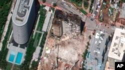 In this satellite image provided by Maxar Technologies, heavy-lift cranes are used to aid in the search and recovery operation at the partially collapsed Champlain Towers South condo building, July 3, 2021, in Surfside, Fla.