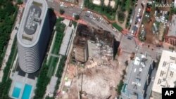 In this satellite image provided by Maxar Technologies, heavy-lift cranes are used to aid in the search and recovery operation at the partially collapsed Champlain Towers South condo building, July 3, 2021, in Surfside, Fla.