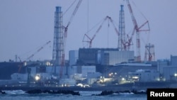 Pembangkit listrik tenaga nuklir Fukushima Daiichi yang hancur akibat tsunami terlihat dari pelabuhan nelayan Ukedo di dekat kota Namie, Prefektur Fukushima, Jepang, 10 Maret 2025, pada malam peringatan 14 tahun bencana gempa bumi dan tsunami 2011. (Kyodo/via REUTERS)