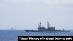 FILE - A Taiwanese navy ship, foreground, monitors a Chinese aircraft carrier, background, near Taiwanese waters in September 2023, in this photo released by the Taiwan Ministry of National Defense.