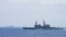 FILE - A Taiwanese navy ship, foreground, monitors a Chinese aircraft carrier, background, near Taiwanese waters in September 2023, in this photo released by the Taiwan Ministry of National Defense.