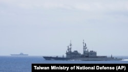 FILE - Taiwanese navy ship Keelung, foreground, monitors the Chinese aircraft carrier Shandong, background, near the Taiwanese waters in September 2023, in this photo released by the Taiwan Ministry of National Defense.