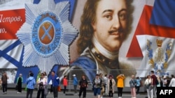 Tourists visit Dvortsovaya Square in front of a giant banner depicting Peter the Great, the founder of Saint Petersburg, in central Saint Petersburg on June 9, 2024.