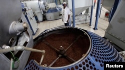 FILE - A worker stands beside a container of roasted coffee beans in a factory in Havana, Cuba, April 7, 2011. 